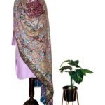 Elegant Kalamkari pashmina shawl featuring vibrant paisley patterns, displayed on a wooden mannequin next to a potted houseplant.