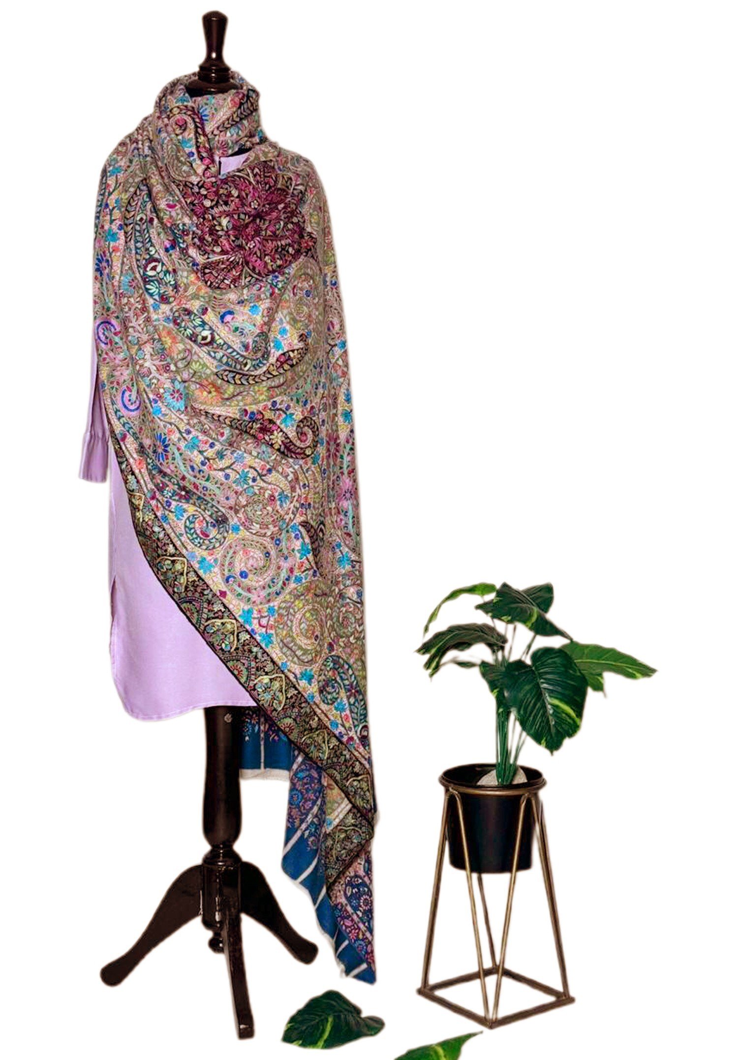 Elegant Kalamkari pashmina shawl featuring vibrant paisley patterns, displayed on a wooden mannequin next to a potted houseplant.
