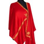 A vibrant red semi-pashmina shawl with intricate golden Baildar embroidery displayed on a mannequin. The shawl is draped to show its rich color and detailed border work.