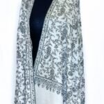 A close-up of a luxurious pure Pashmina Jaal shawl featuring intricate, delicate hand-embroidered floral and vine patterns in a traditional Kashmiri style. The fabric appears soft and finely woven, showcasing the detailed 'jaal' (net) work.